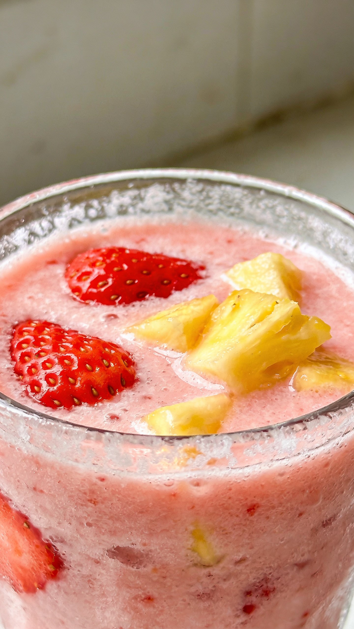 closeup strawberry pineapple smoothie in clear glass, frosty, creamy