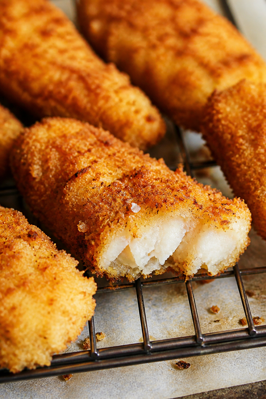 Close-up detail: Golden-brown Parmesan-panko fish sticks just out of the air fryer, ultra-crispy cru