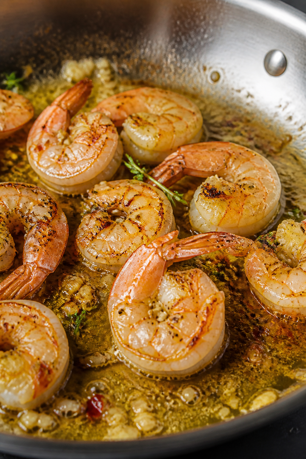 Cooking process close-up: Searing large shrimp in a stainless-steel skillet with a glossy lemon-garl