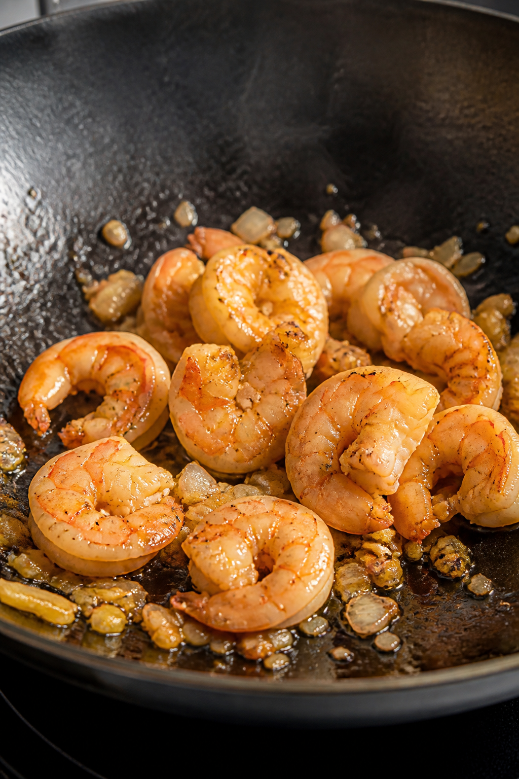 Cooking process close-up: Searing shrimp in a carbon-steel wok over medium-high heat, shrimp just tu