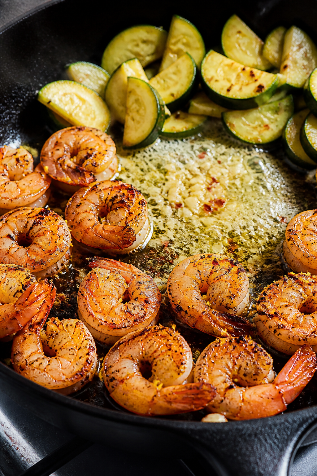Cooking process close-up: Shrimp searing in a hot skillet in a single layer with visible golden edge