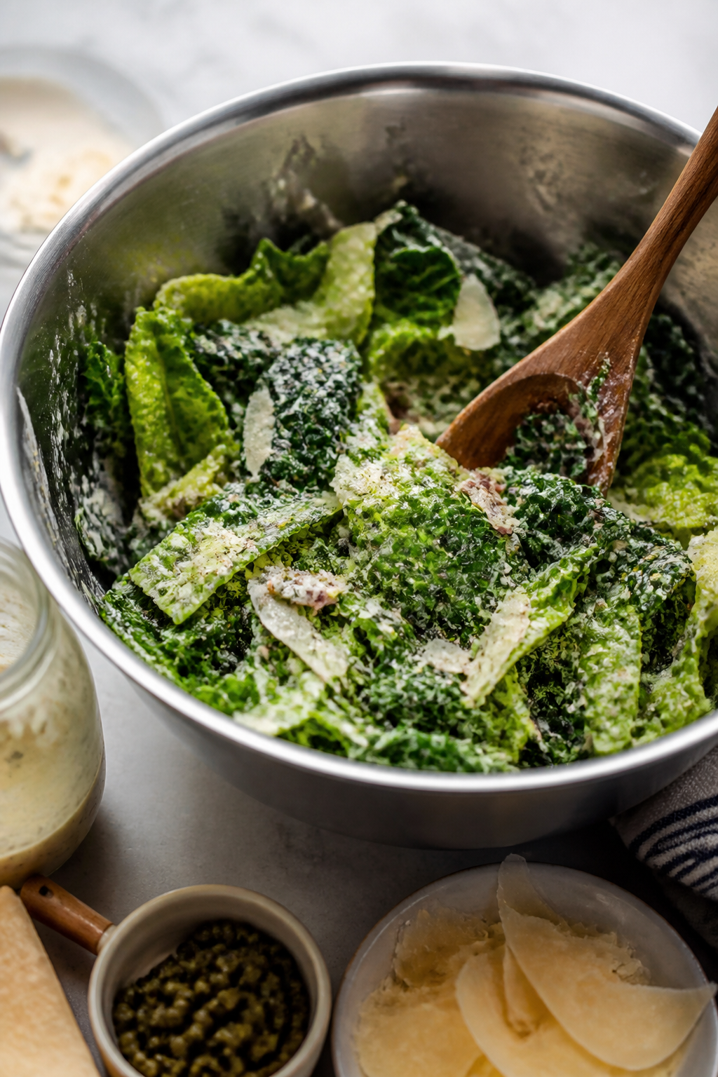 Cooking process: Tossing chopped romaine and lacinato kale in a large stainless bowl with creamy Gre