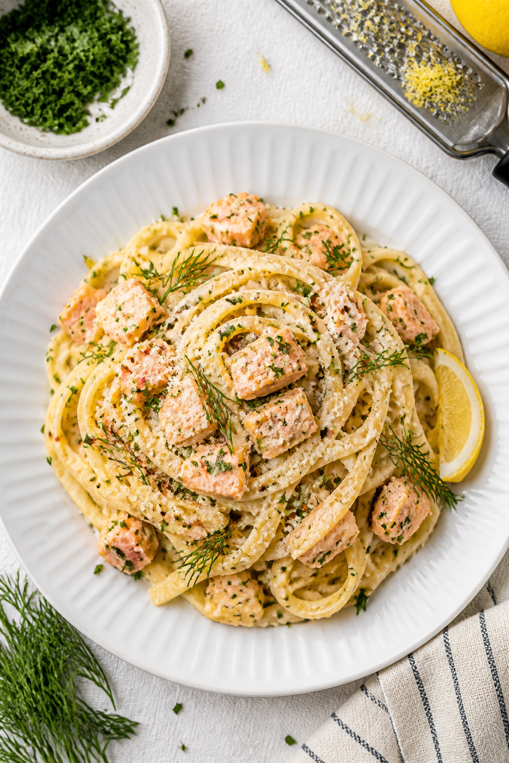 Final plated dish, top view: Overhead shot of Healthy Creamy Salmon Pasta twirled into a nest on a w