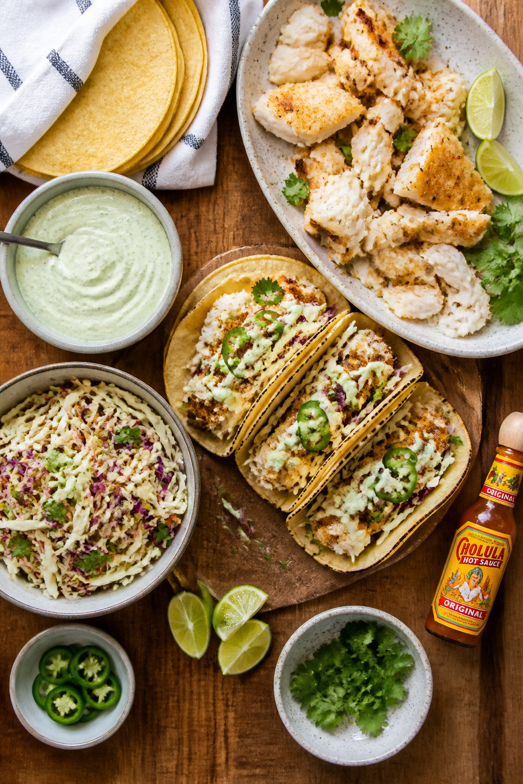 Tasty overhead spread: of a taco assembly board—separate small bowls of zesty lime crema and cilan