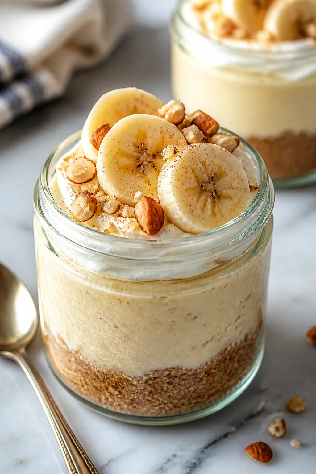 Close-up detail: A chilled banana cream cheesecake jar with visible layers—crumbly almond flour-ci