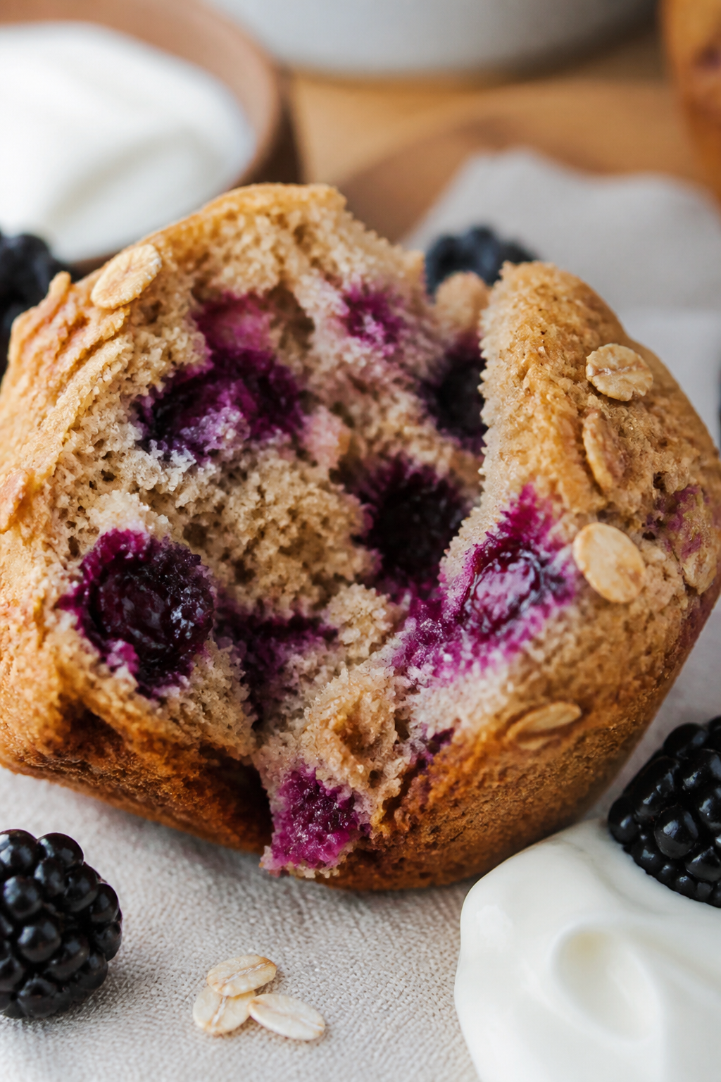 Close-up detail: A freshly baked blackberry oat muffin torn open to reveal juicy blackberry pockets