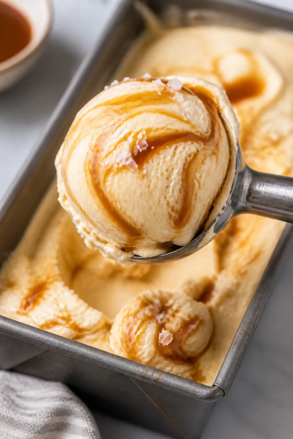 Close-up detail: A heaping scoop of salted caramel protein ice cream just lifted from a chilled loaf