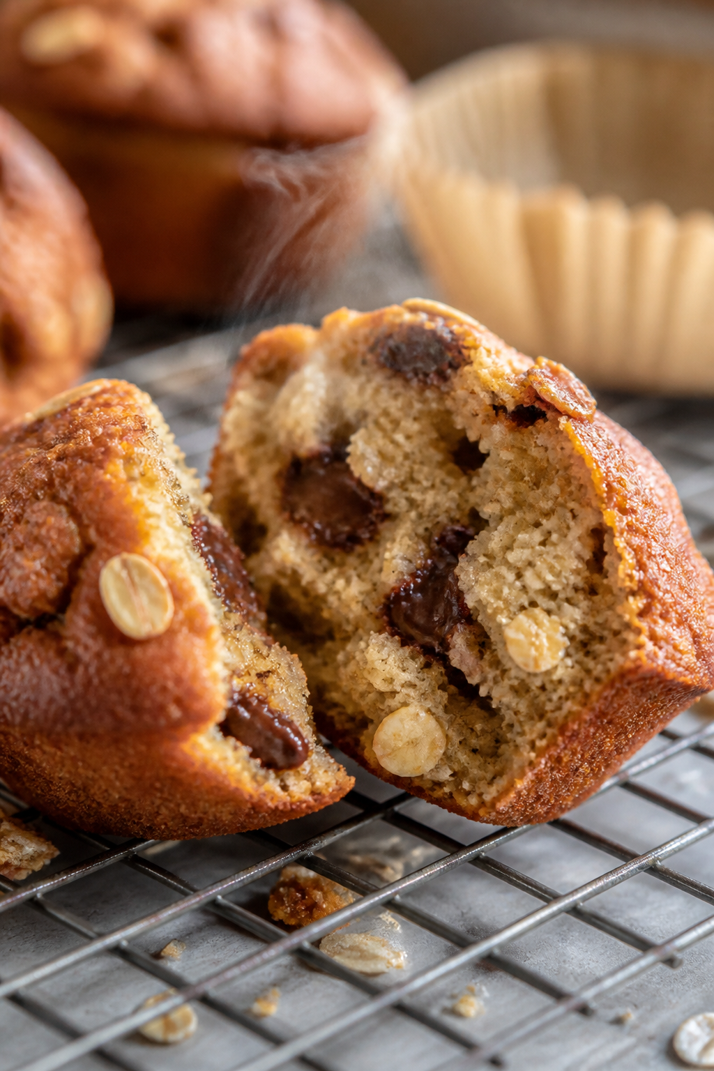 Close-up detail: A just-baked banana oatmeal muffin torn open on a cooling rack, steam faintly risin