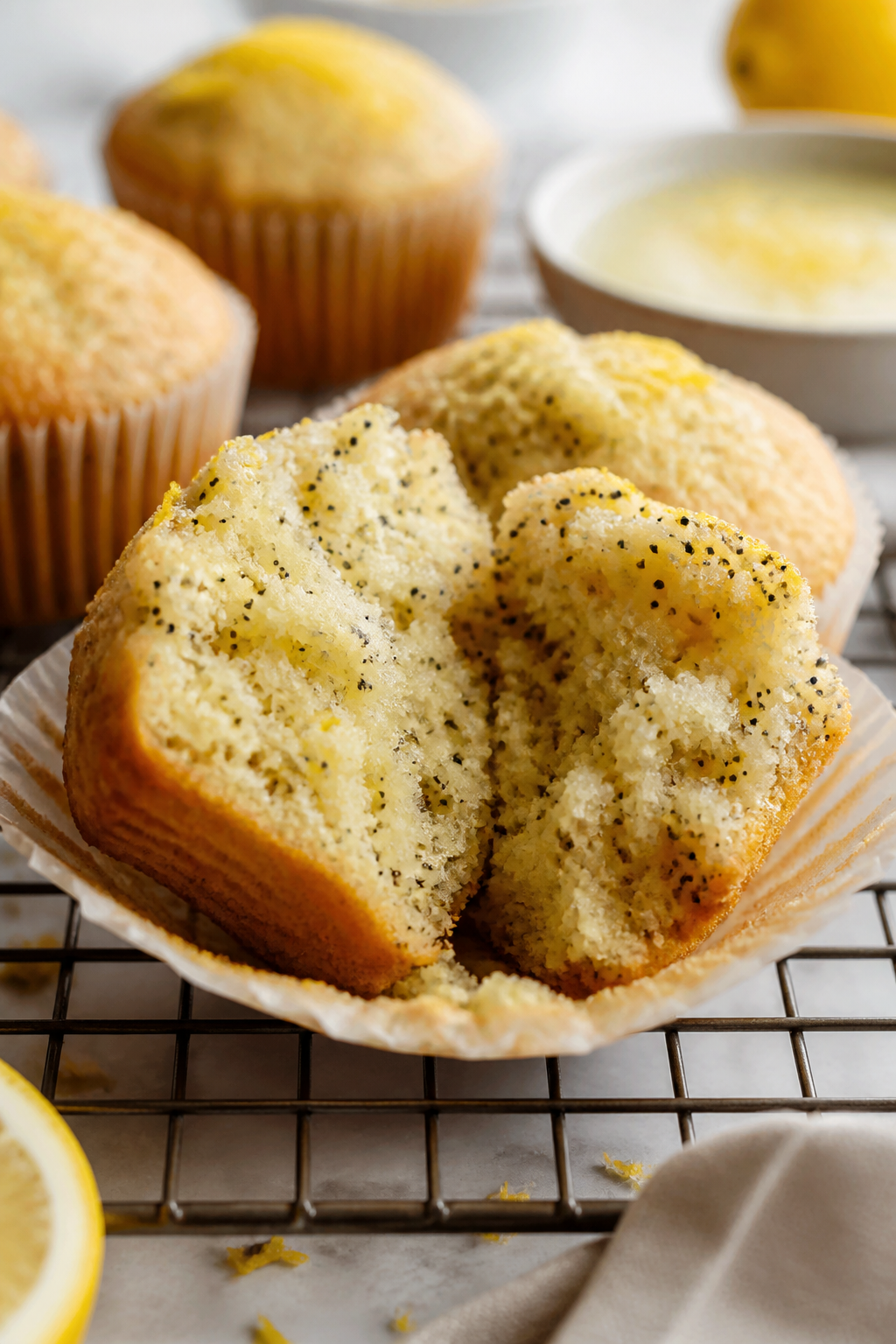 Close-up detail: A just-baked lemon poppy seed protein muffin torn open on a wire rack, showing a mo