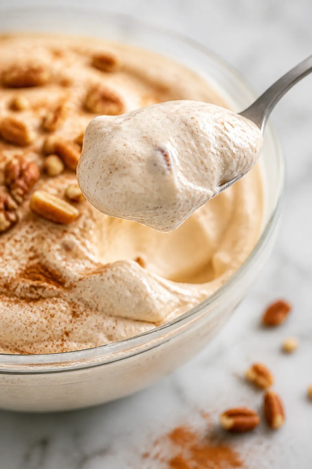 Close-up detail: A spoonful of cinnamon cheesecake fluff just lifted from a chilled glass bowl, show