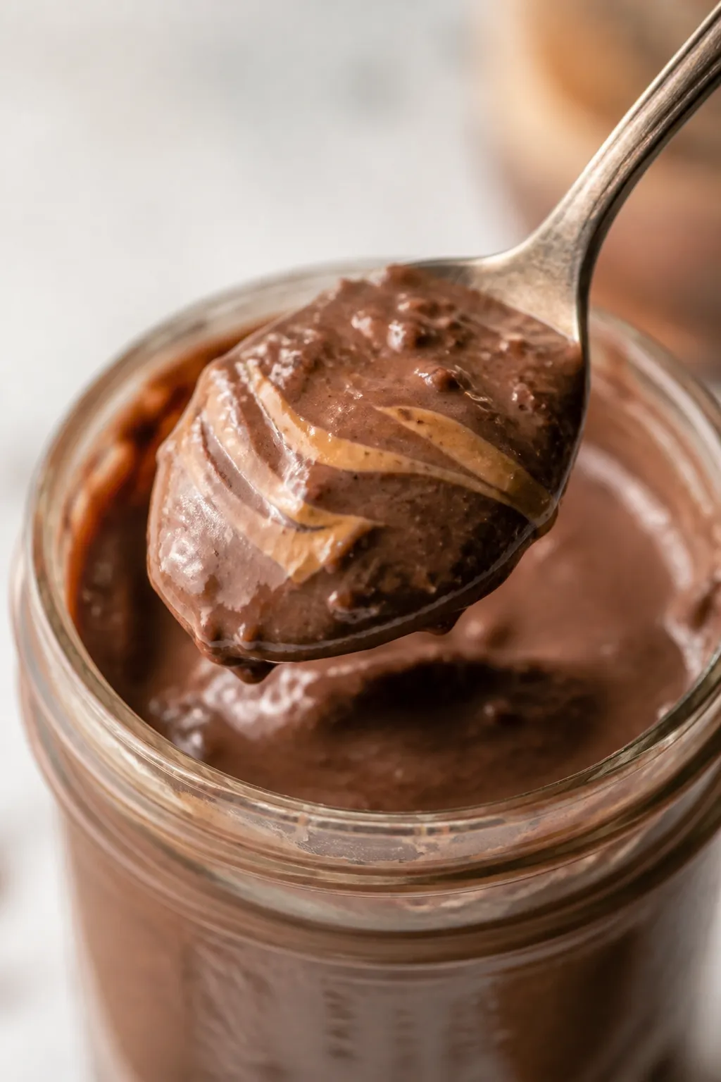 Close-up detail: A spoonful of high-protein chocolate peanut butter pudding being lifted from a chil