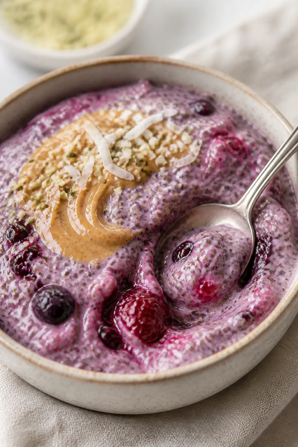 Close-up detail: Creamy mixed berry chia pudding after overnight chill, spoon dragged through to rev