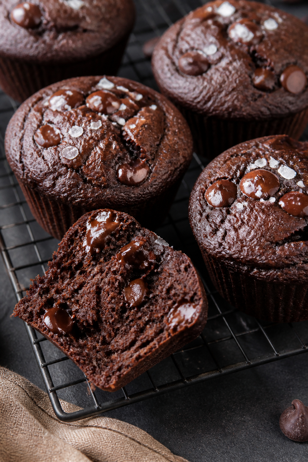 Close-up detail: Freshly baked double chocolate protein muffins resting on a wire cooling rack, dome
