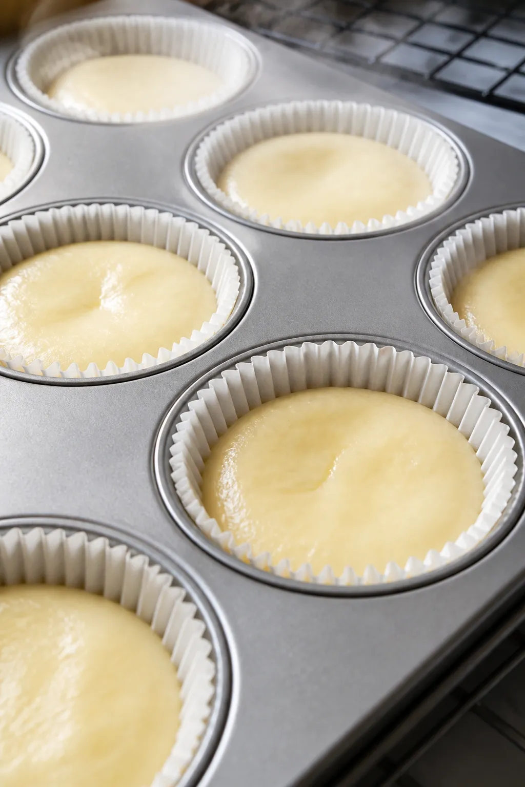 Close-up detail: Freshly baked vanilla cheesecake protein bites still in a lined muffin tin, edges s