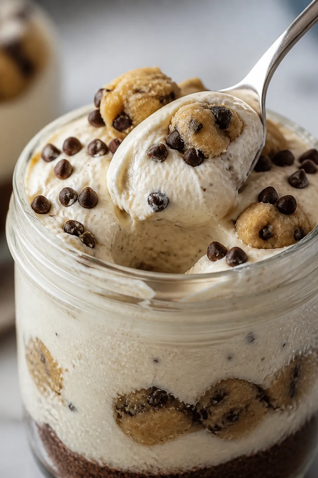Close-up detail shot: A spoon scooping into a layered High Protein Low Carb Cookie Dough Cheesecake 