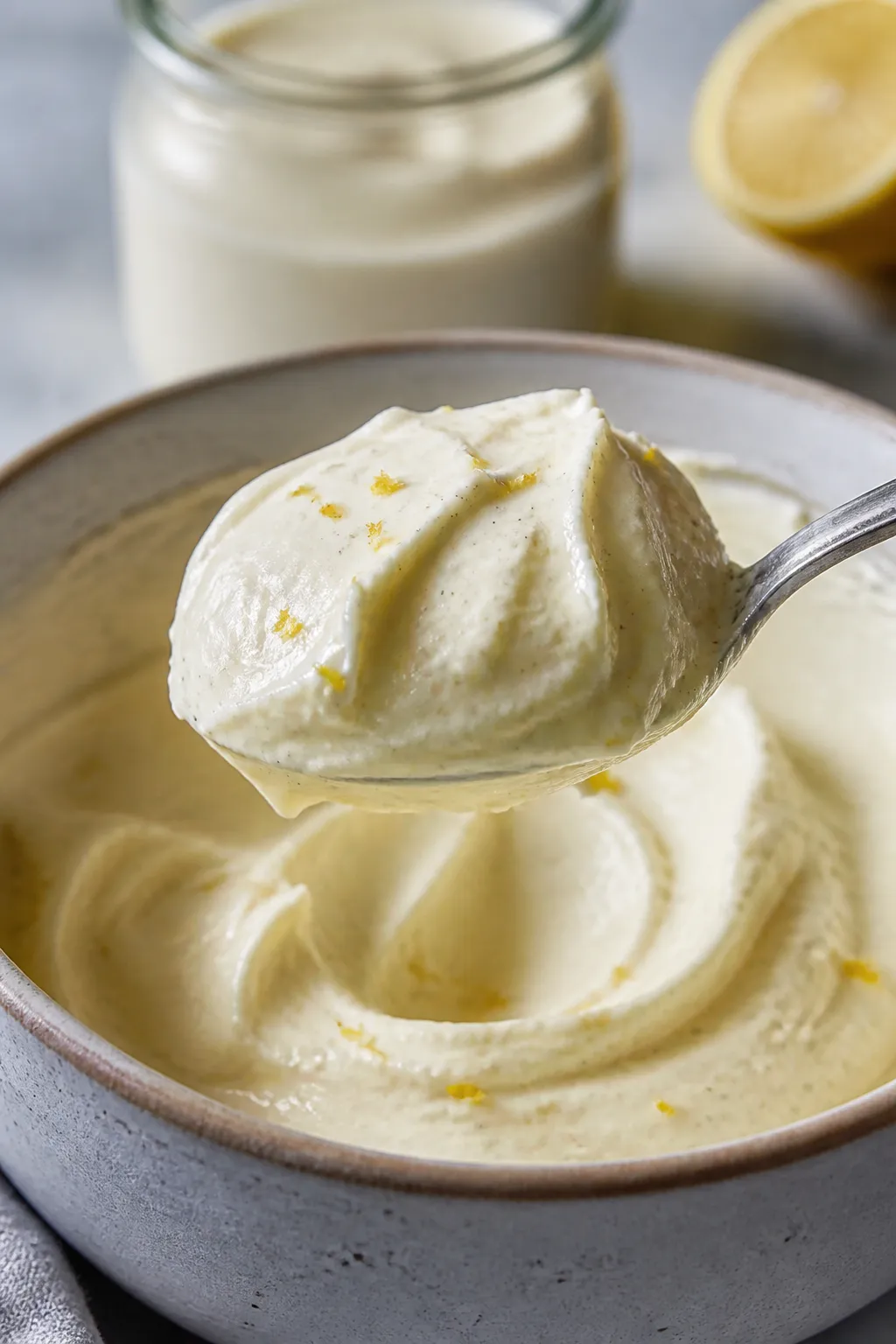Close-up detail shot: a spoonful of creamy cheesecake filling being lifted from a mixing bowl, showi
