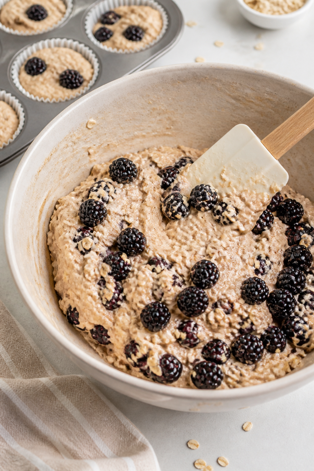 Cooking process: Batter portioning scene with a sturdy spatula gently folding plump blackberries int