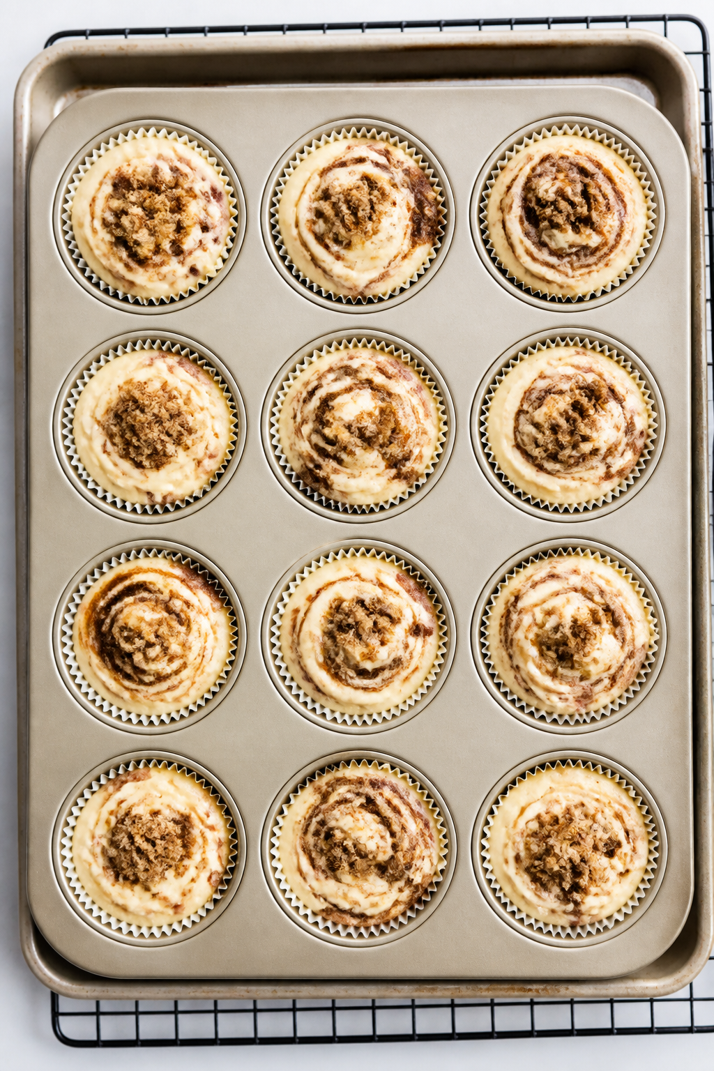 Cooking process: Overhead shot of a lined 12-cup muffin tin just before baking, each cup layered wit