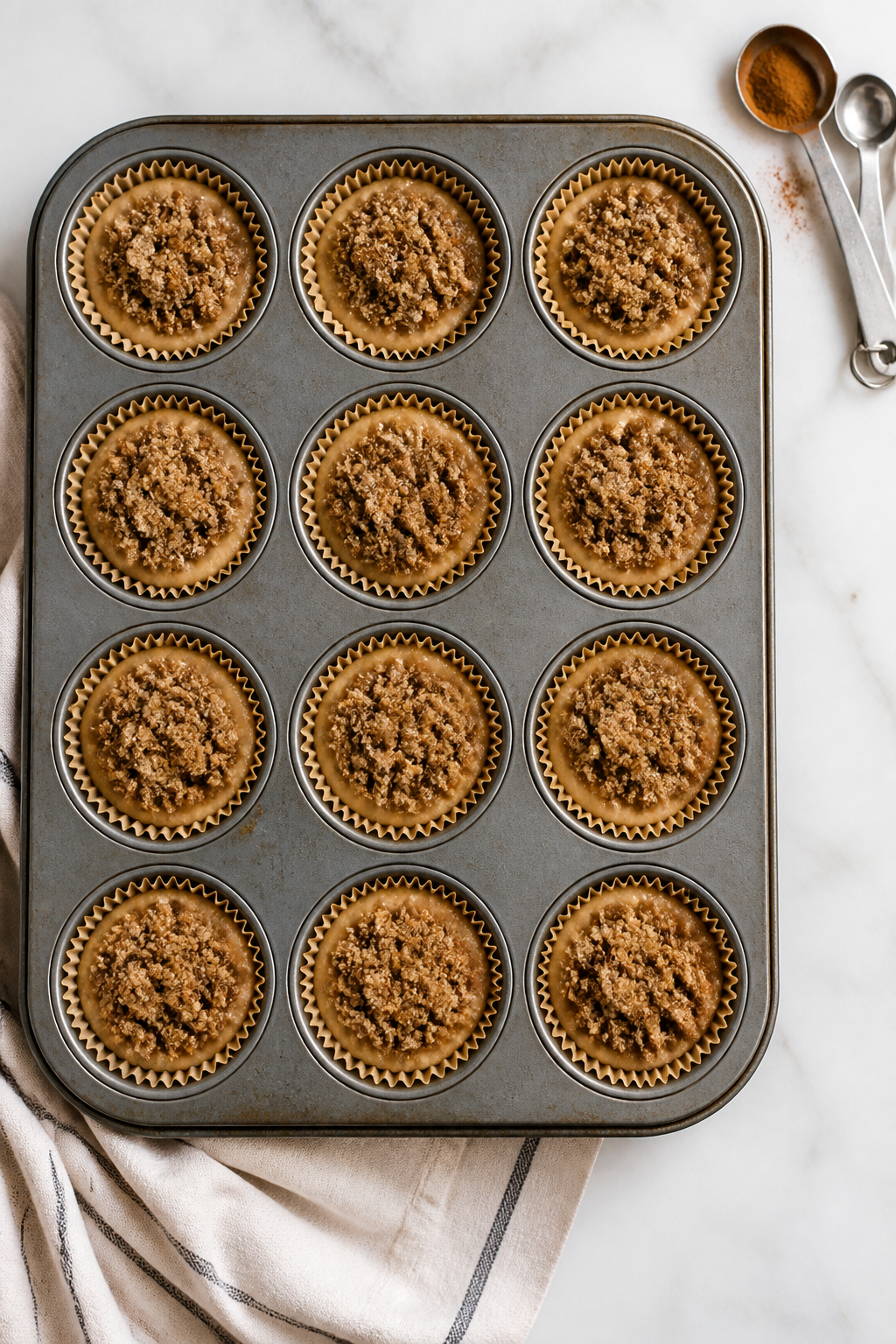 Cooking process: Overhead shot of a lined 12-cup muffin tin filled two-thirds with thick batter, eac