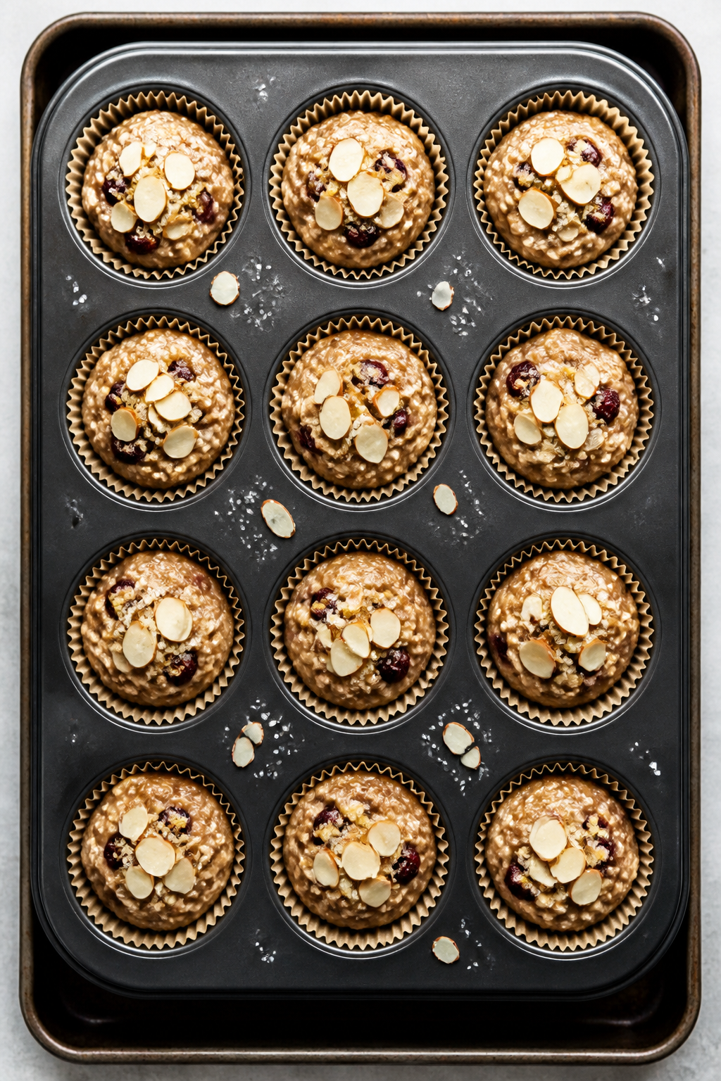 Overhead “ready to bake” top view: A 12-cup muffin tin filled evenly with Cherry Almond Protein 