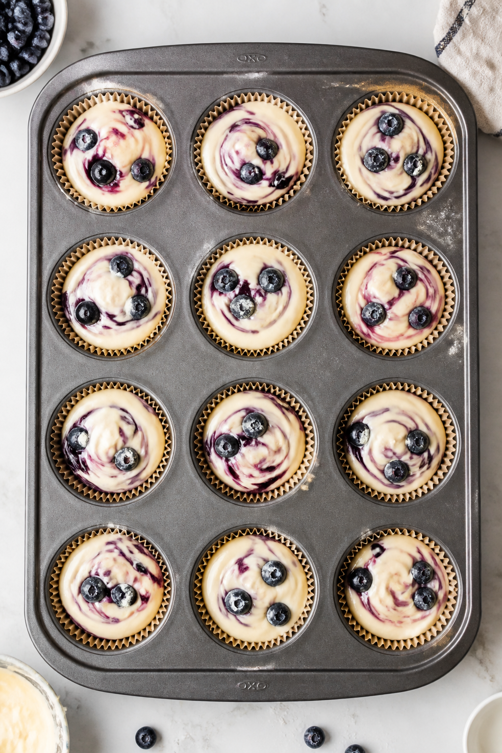 Tasty top view: Overhead shot of a 12-cup muffin tin lined with lightly misted papers, each cup fill