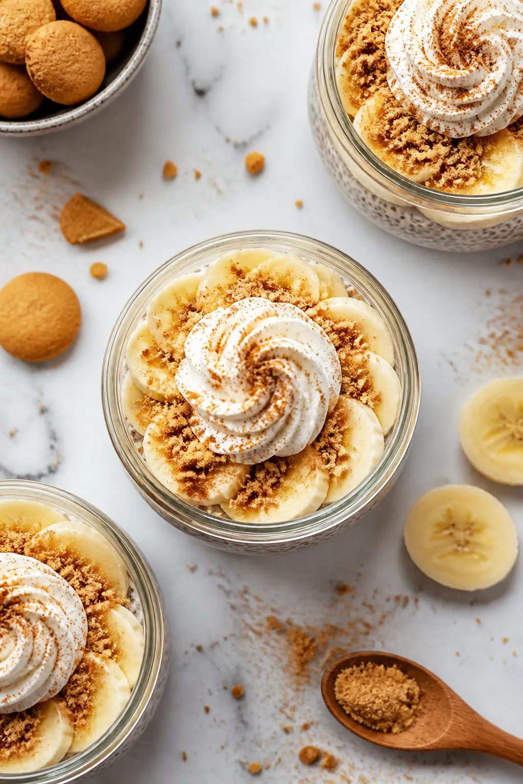Tasty top view: Overhead shot of layered banana cream pie chia pudding in clear glass jars—base of