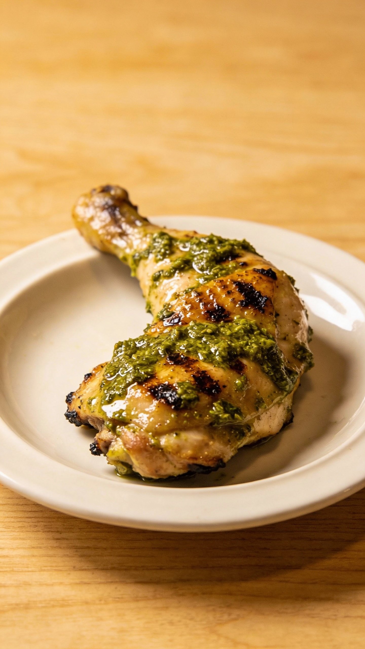 single plated pesto chicken thigh, basil pesto gloss, broiled char spots