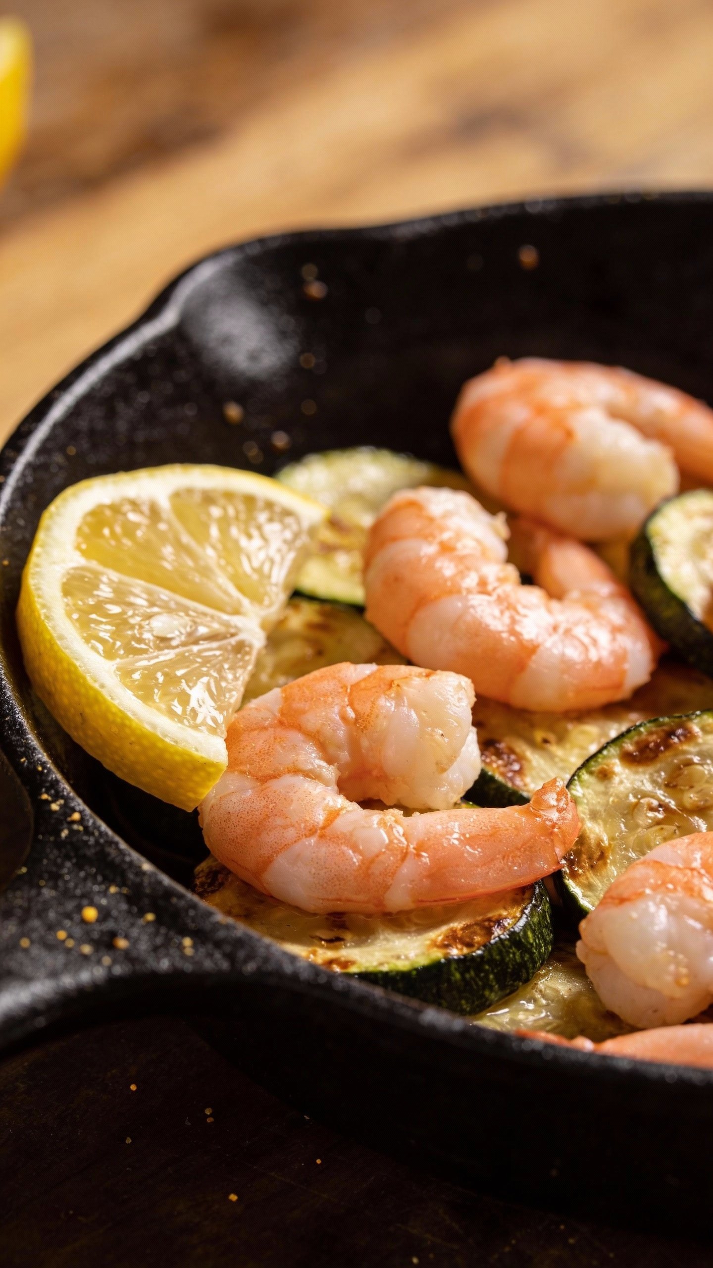 closeup shrimp zucchini skillet in cast-iron, lemon wedge garnish