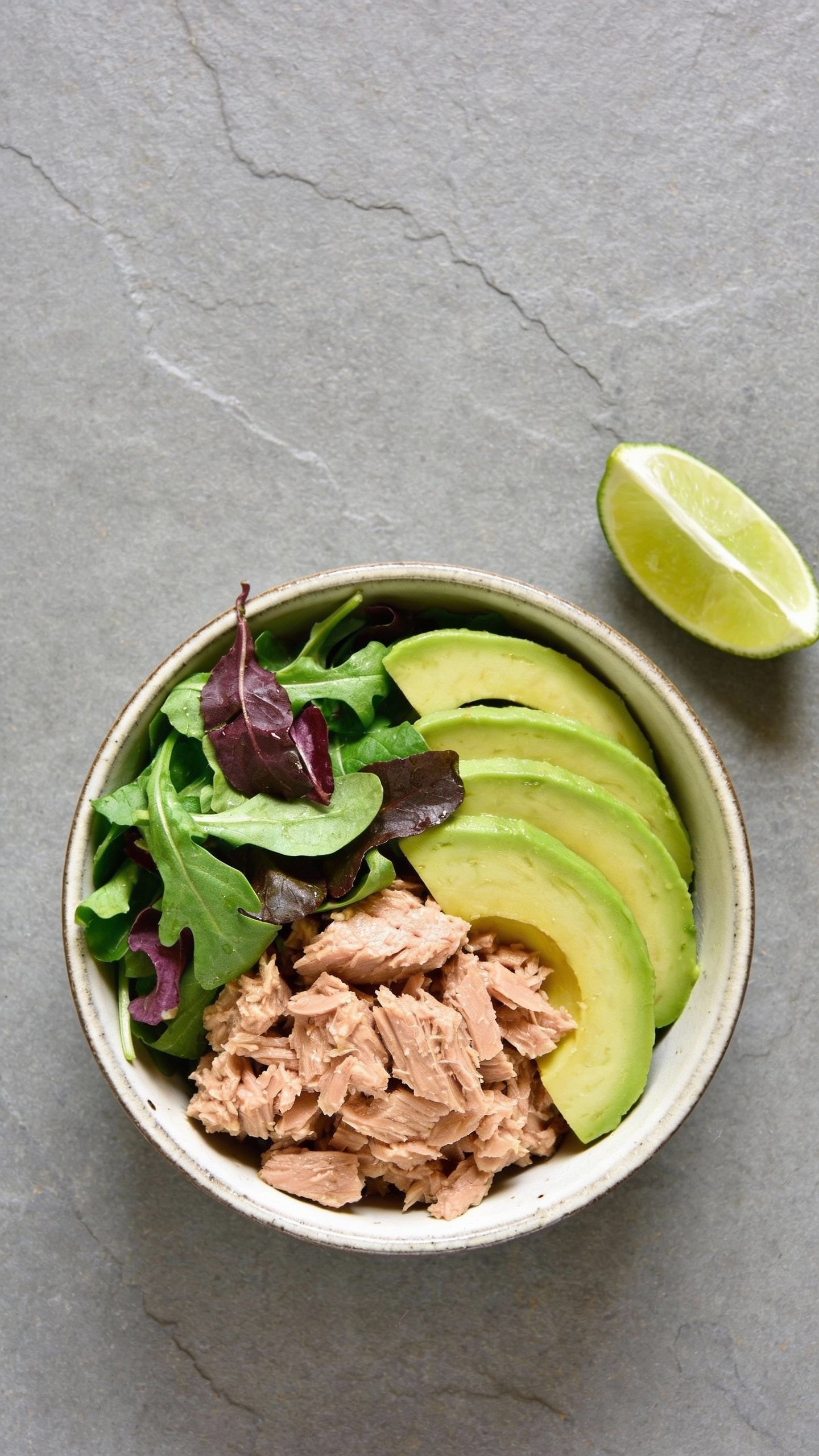 overhead tuna avocado bowl with lime wedge on slate background