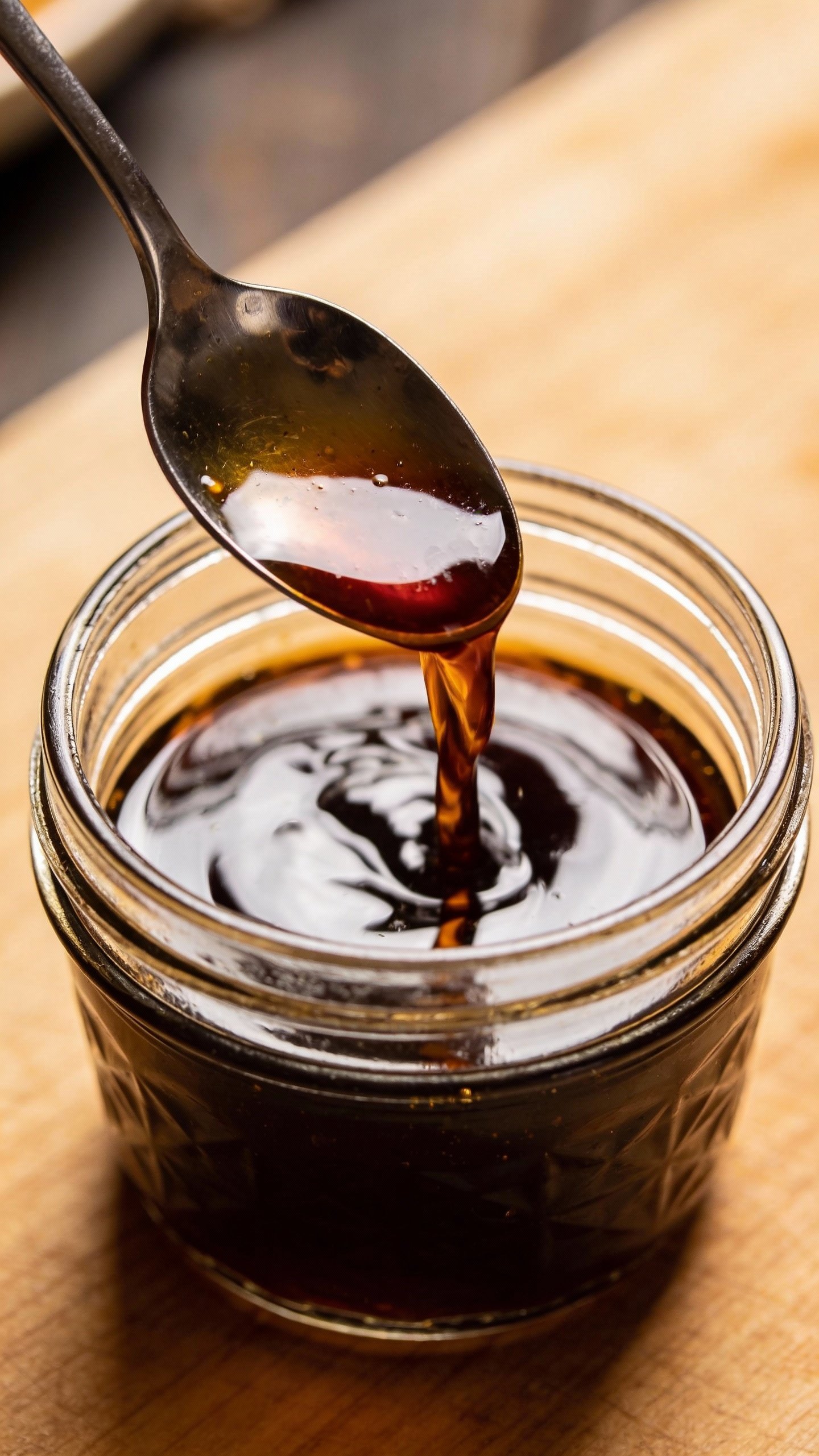 spoon dipping into homemade teriyaki sauce in glass jar