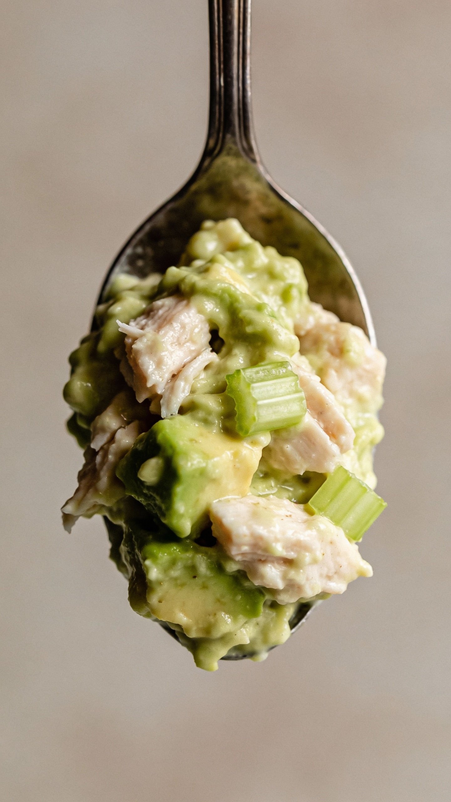 spoonful of creamy avocado chicken salad against neutral backdrop