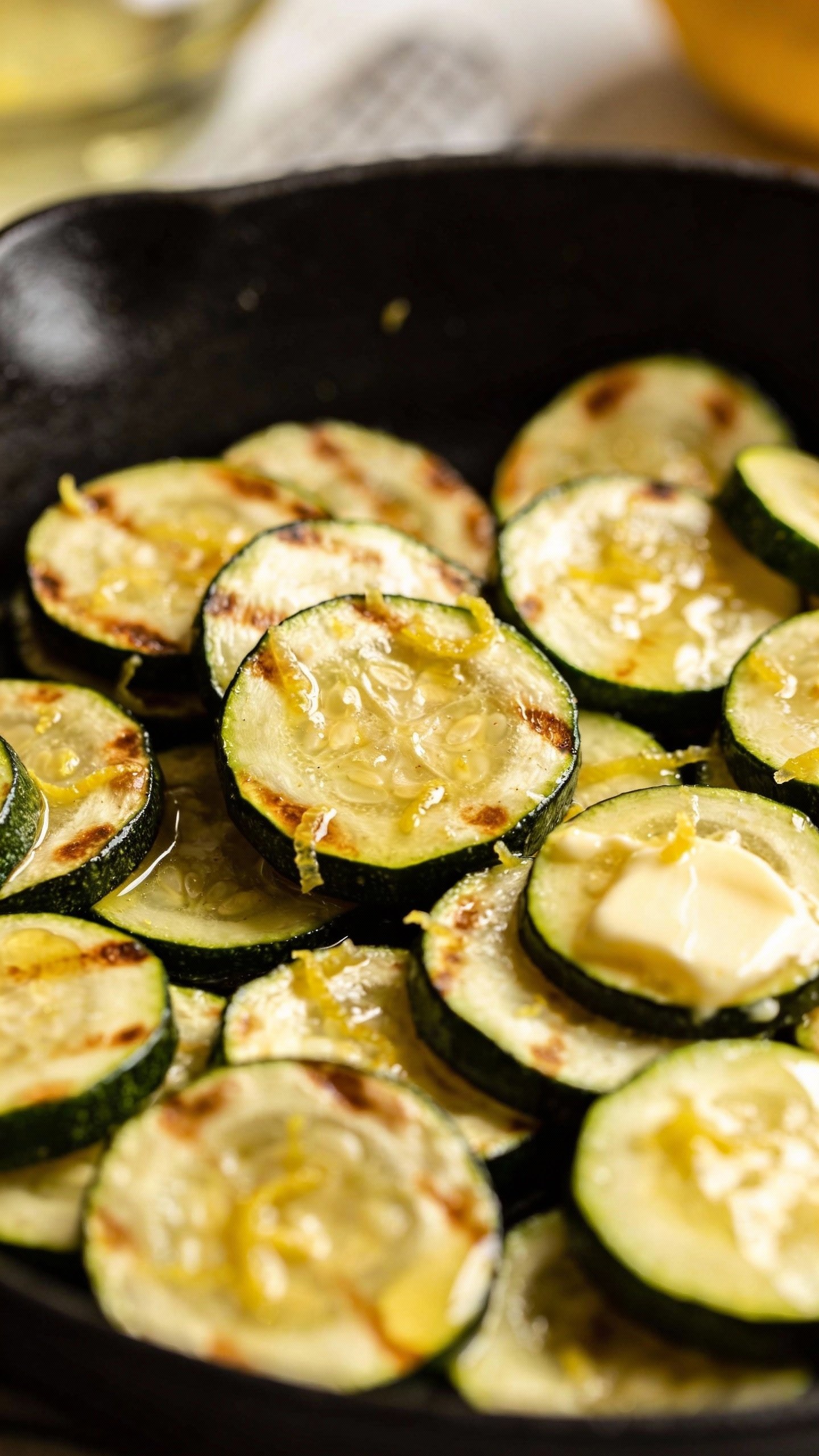 closeup skillet of garlic-butter zucchini slices with lemon zest