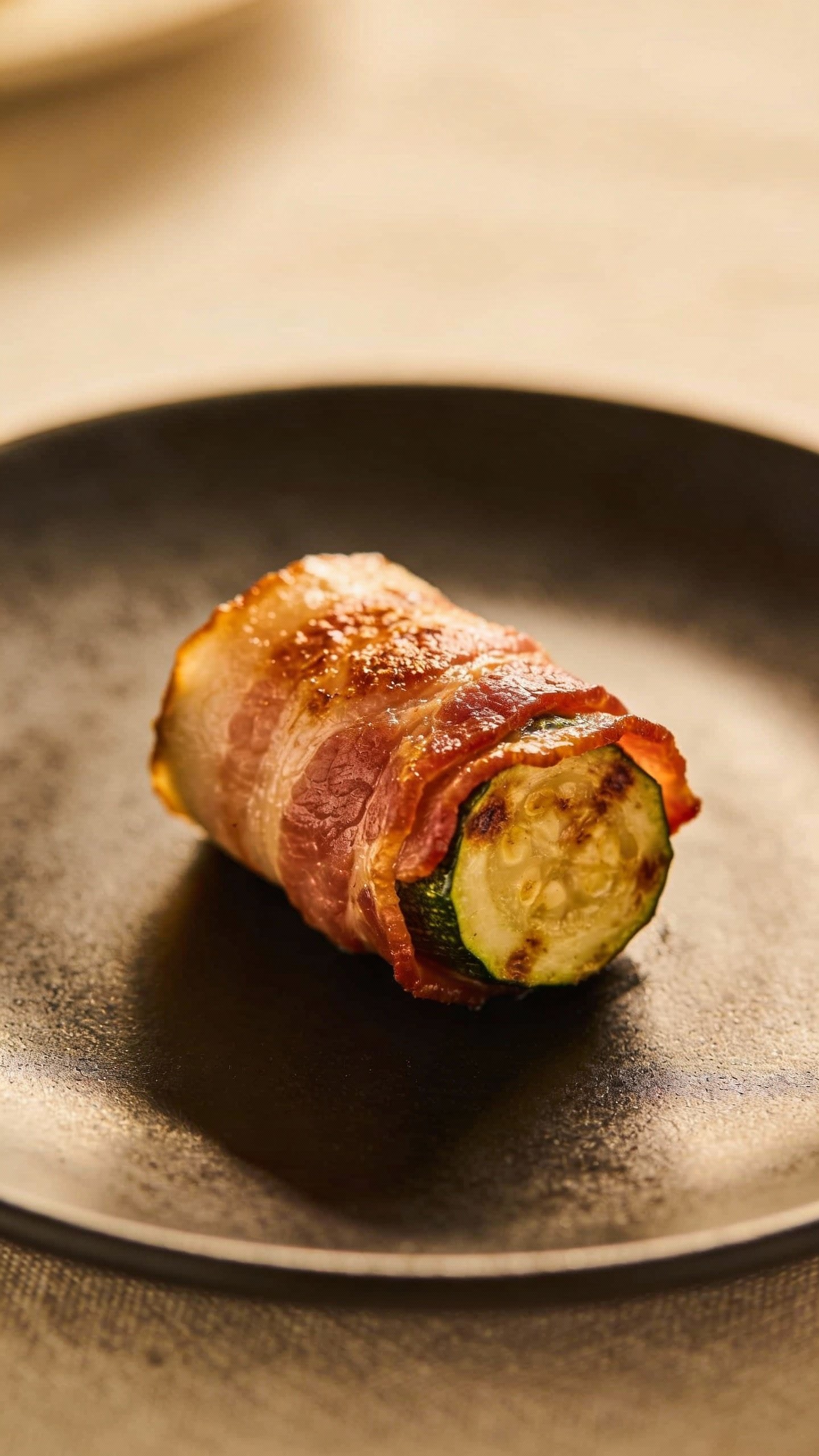 single bacon-zucchini bite on small matte black plate