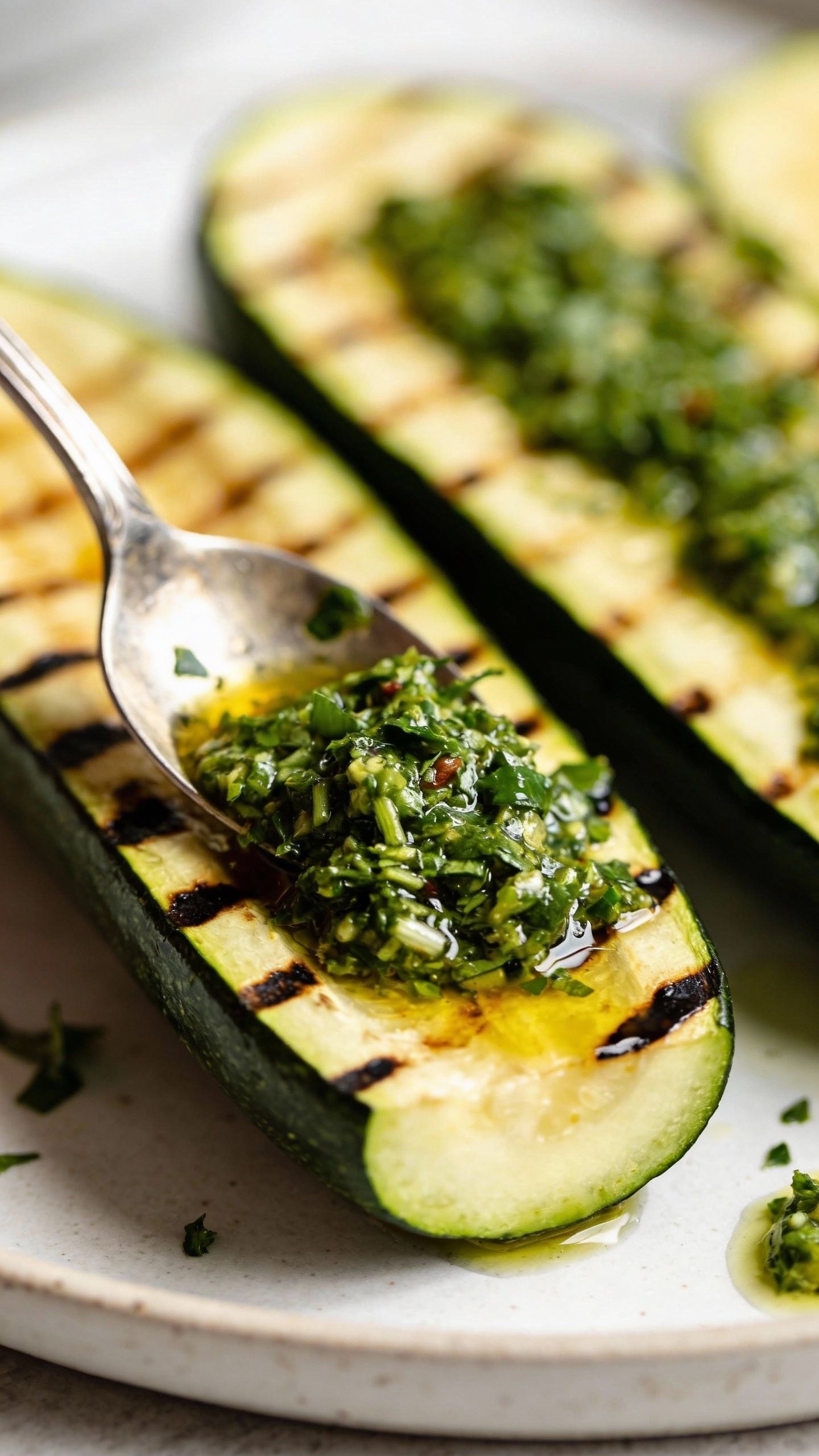 spoonful of bright chimichurri over grilled zucchini end-cut