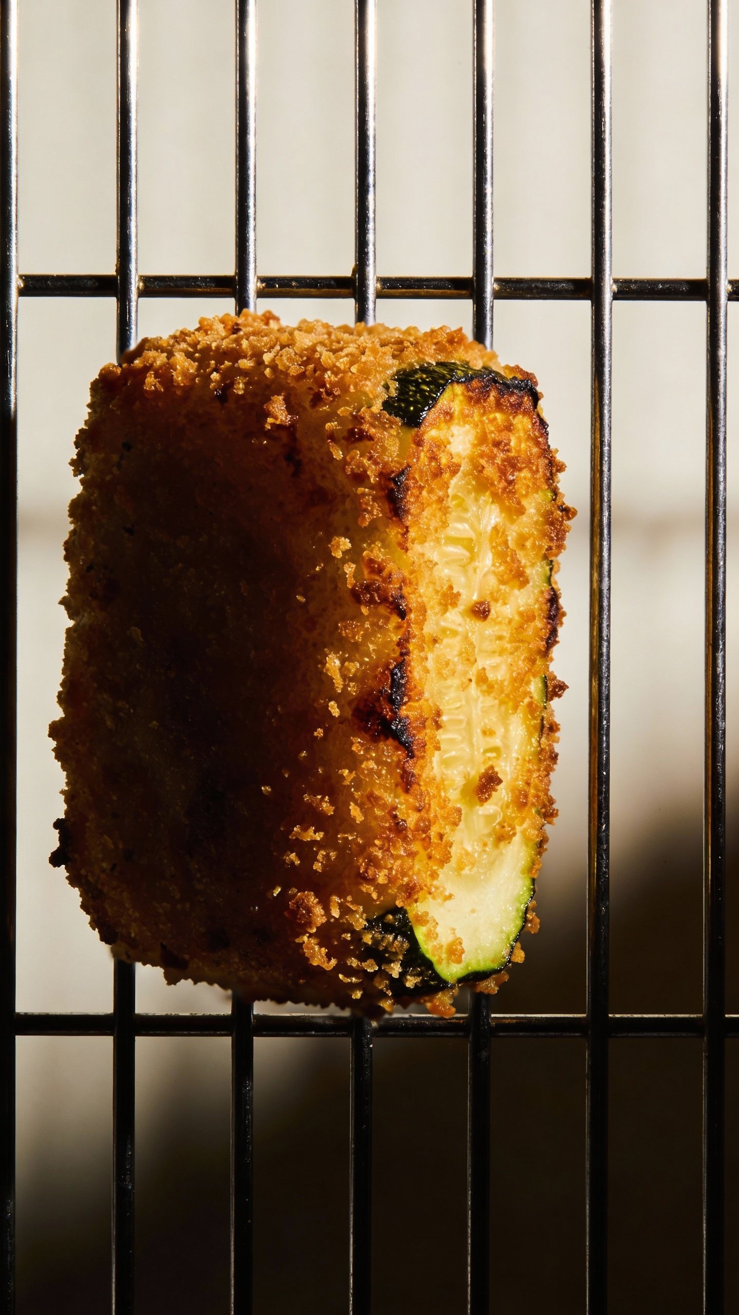 crispy zucchini tot on wire rack, dramatic side lighting