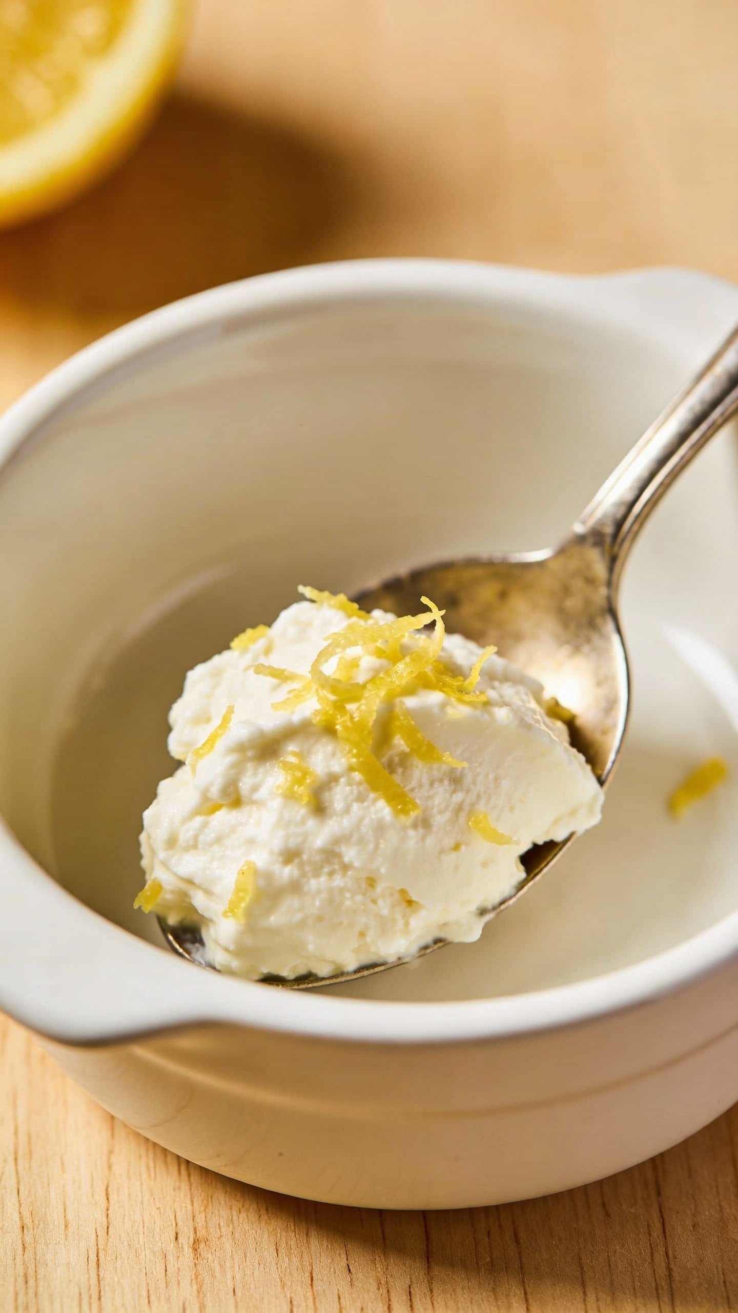 spoonful of creamy ricotta with lemon zest in bowl