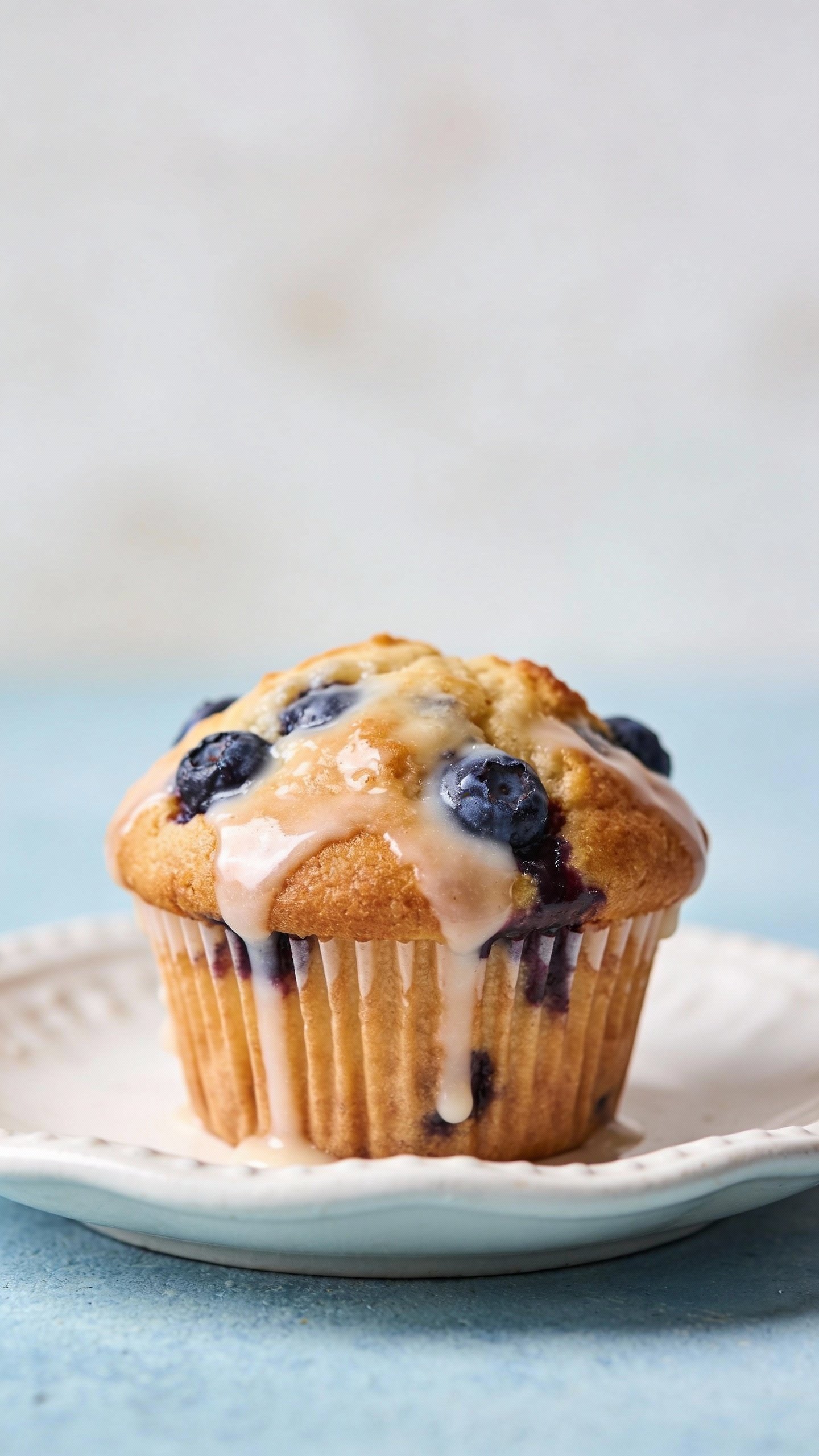 single glazed blueberry muffin on white ceramic plate