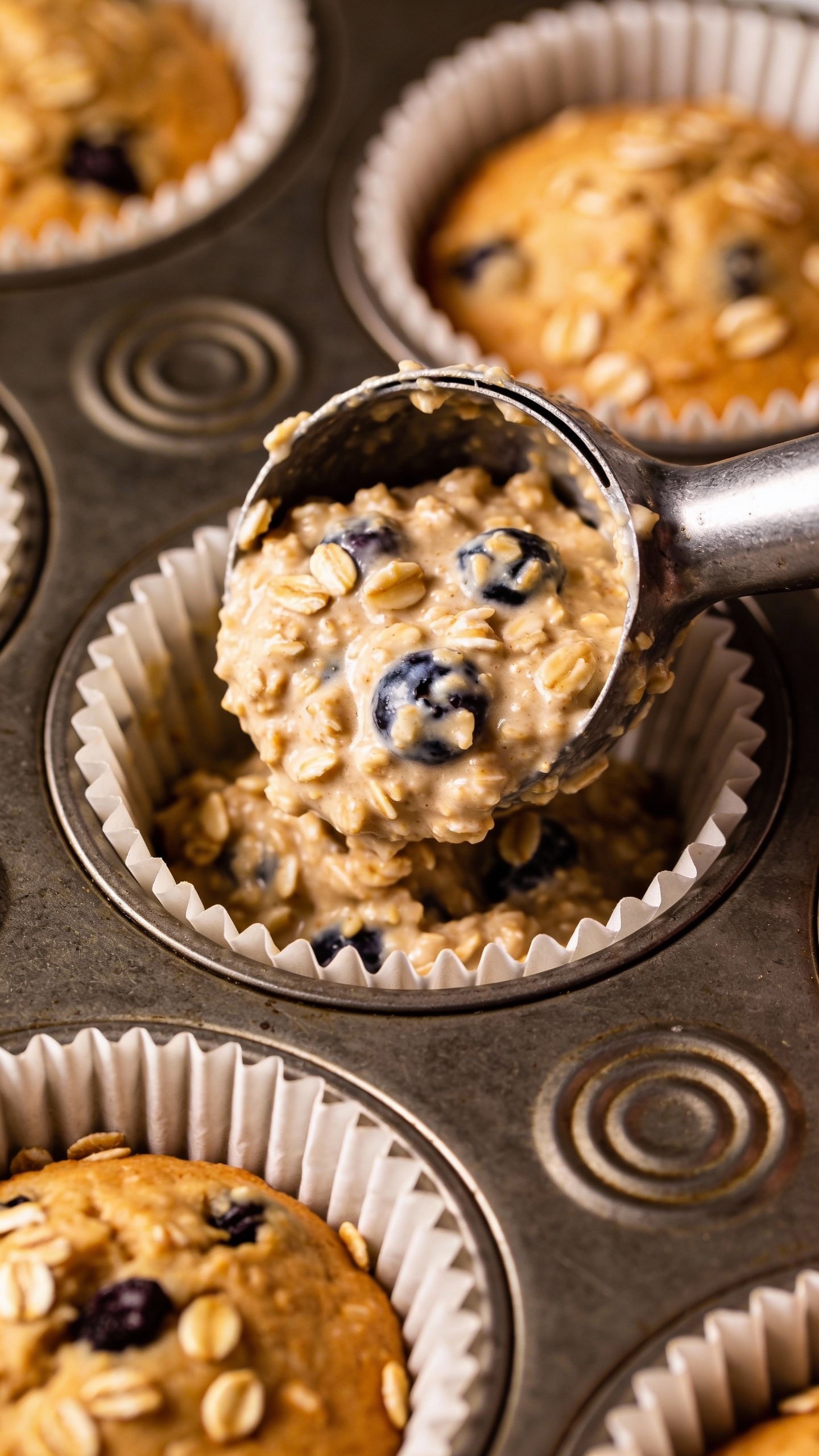 single oatmeal blueberry batter scoop in lined muffin tin