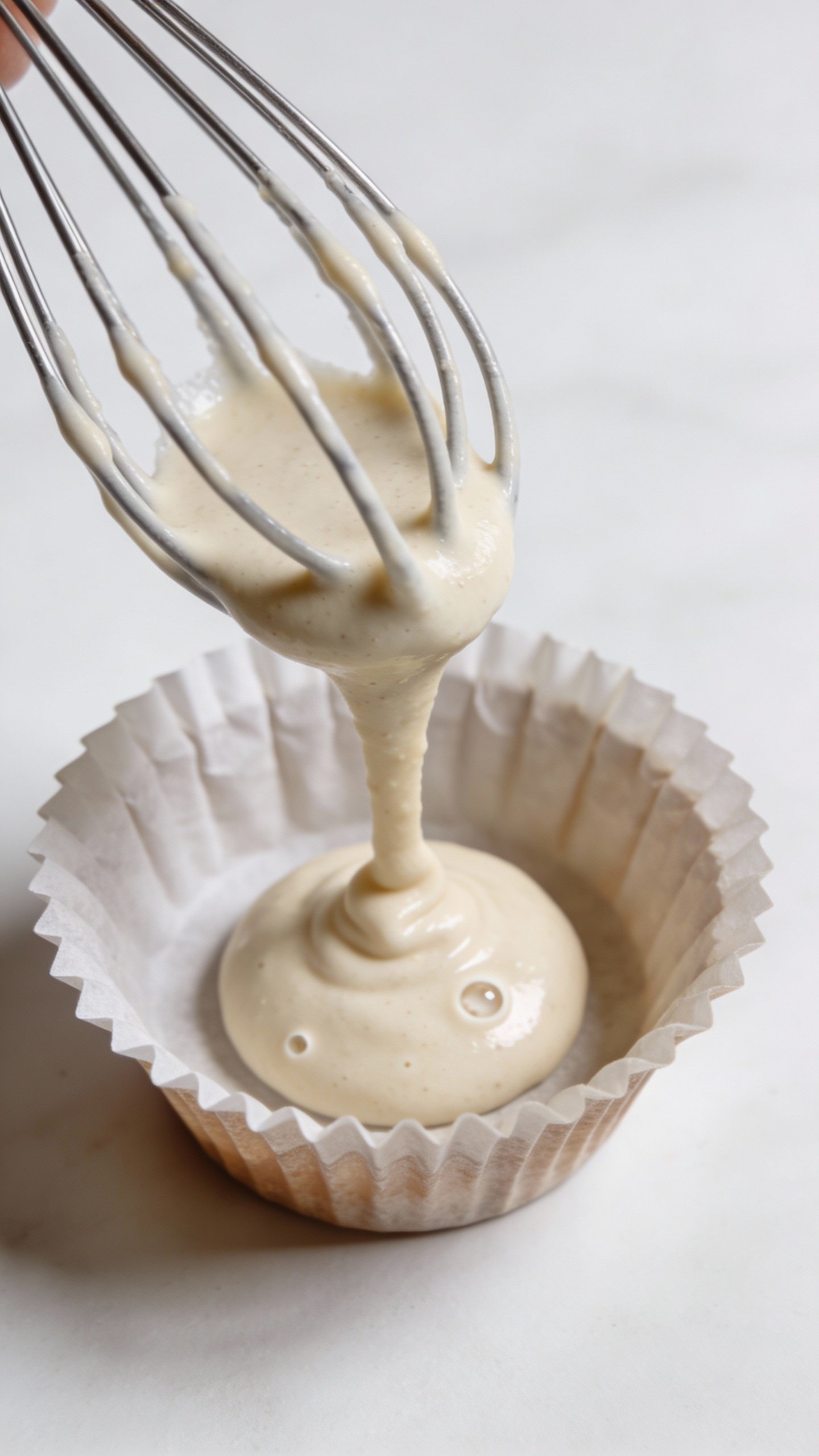 whisk drizzling vegan batter into one muffin cup, overhead