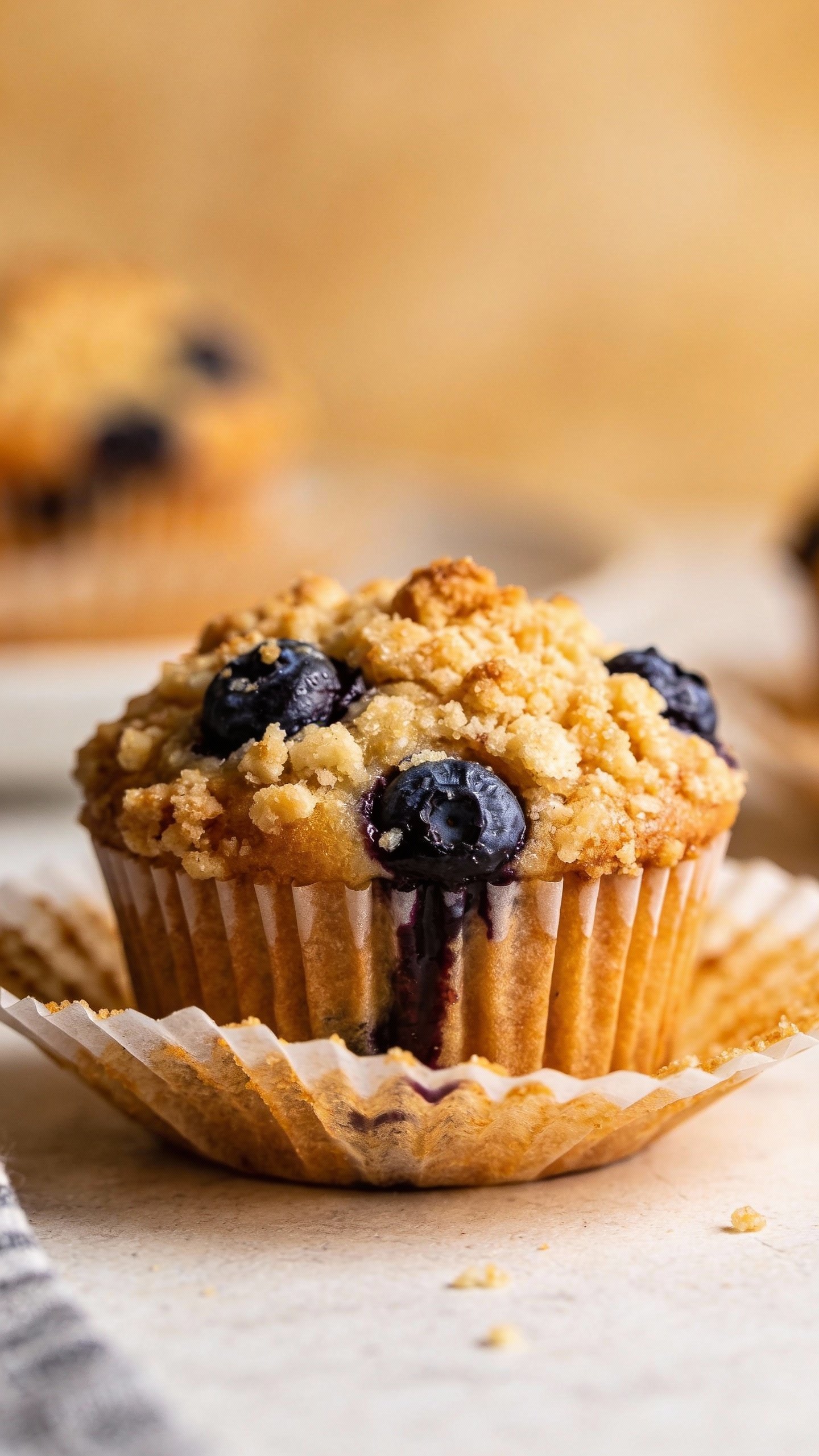 single blueberry muffin with golden crumble, parchment liner