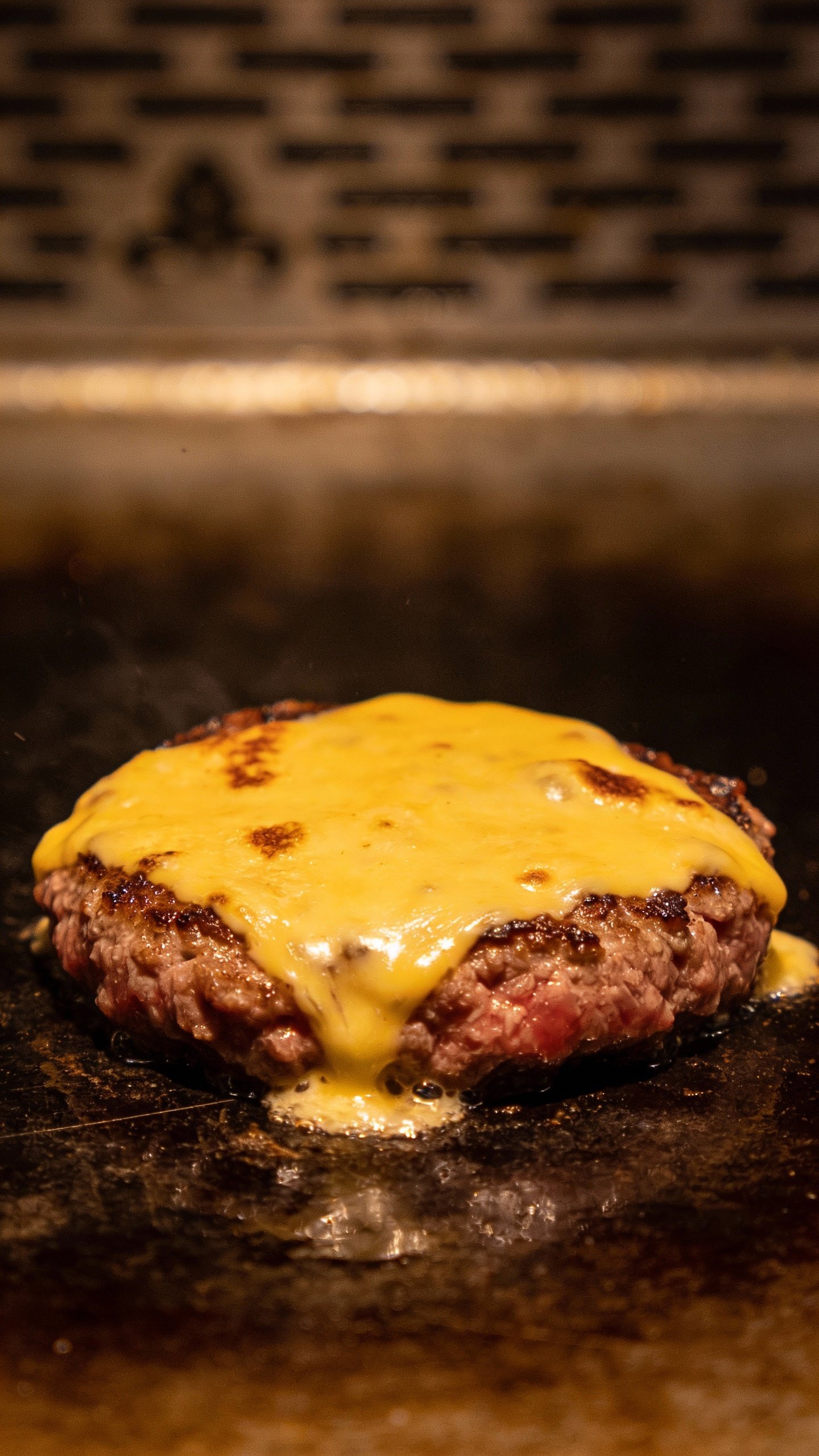 single lean beef patty with melted cheese on griddle