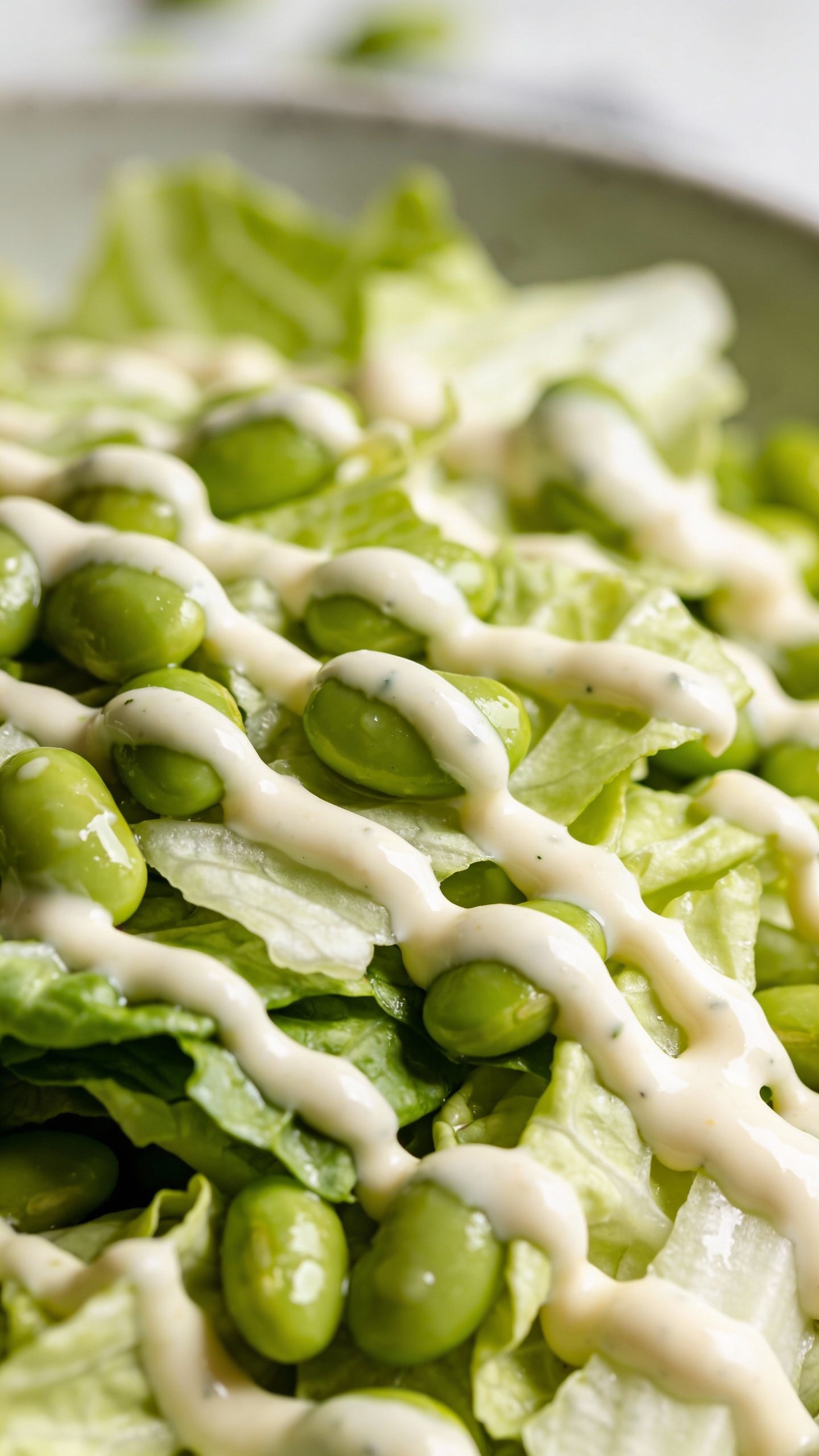 closeup cabbage edamame salad with creamy dressing drizzle