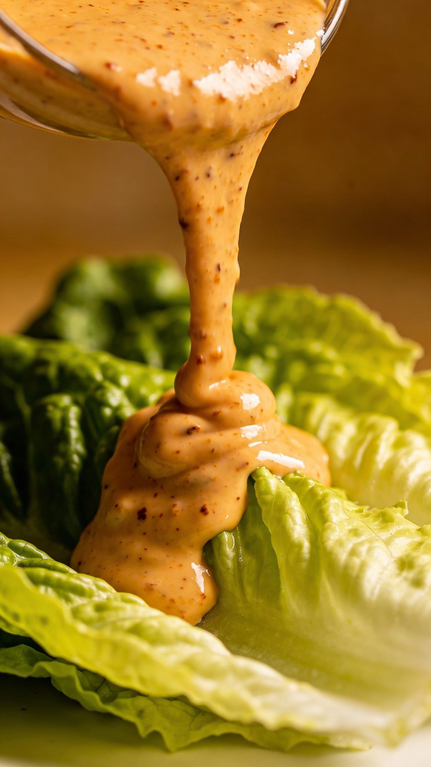 creamy chipotle yogurt dressing drizzling over romaine lettuce