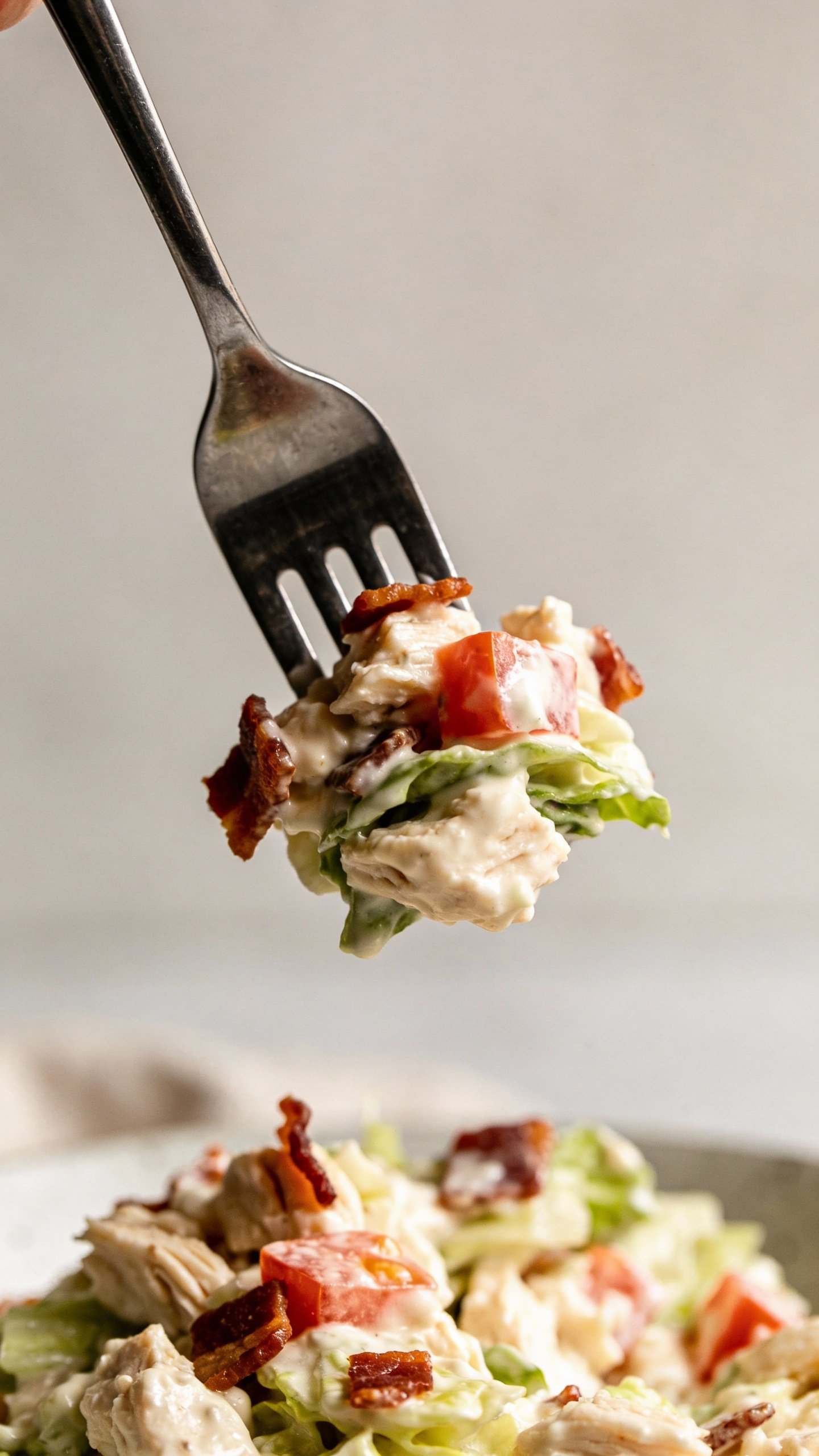 forkful of creamy BLT chicken salad against neutral backdrop