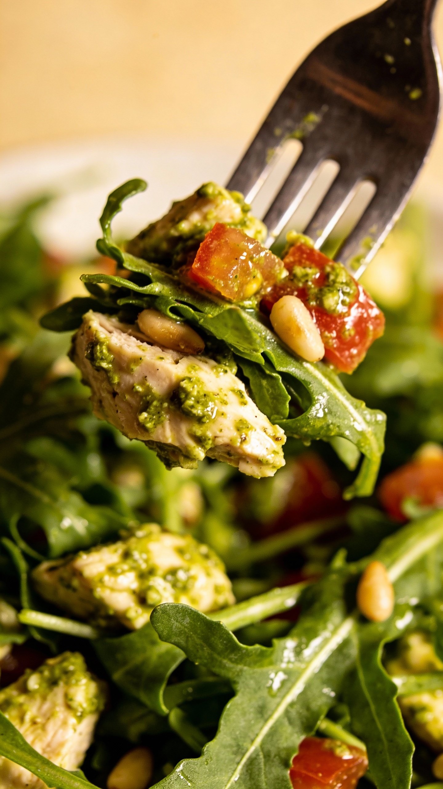 single forkful of pesto chicken salad over arugula, macro shot