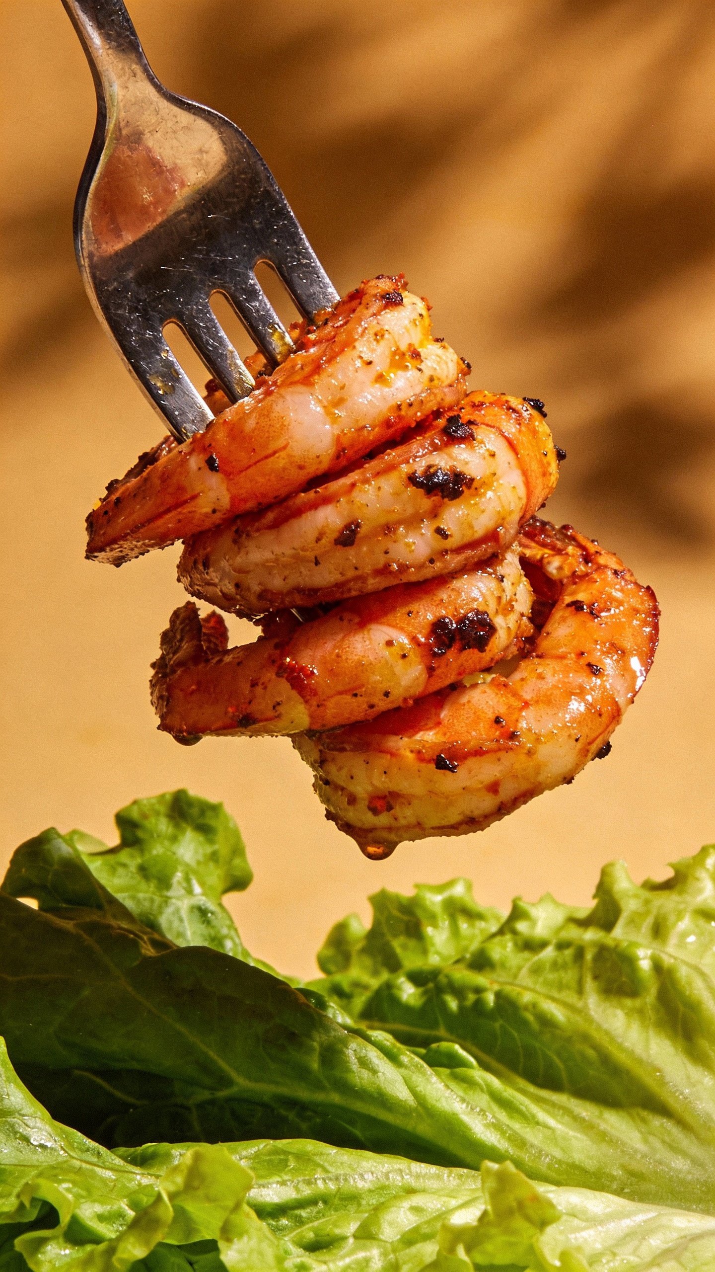 seared Cajun shrimp on fork above crisp greens, studio lighting