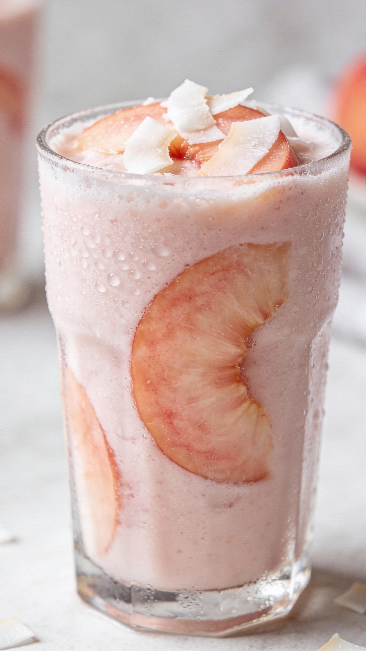 frosty peach coconut smoothie in clear glass, closeup