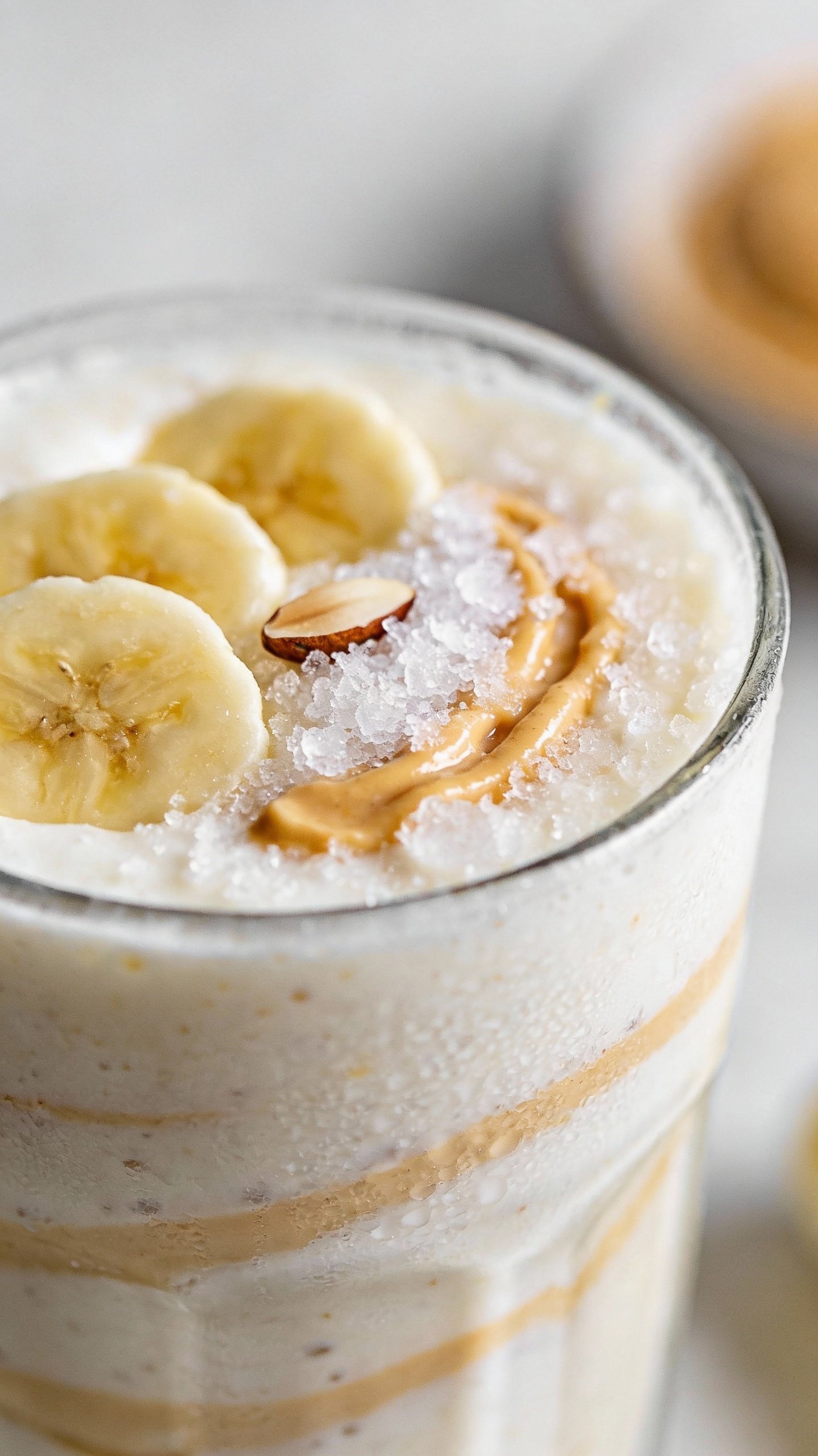 frosty banana almond butter smoothie in clear glass, closeup