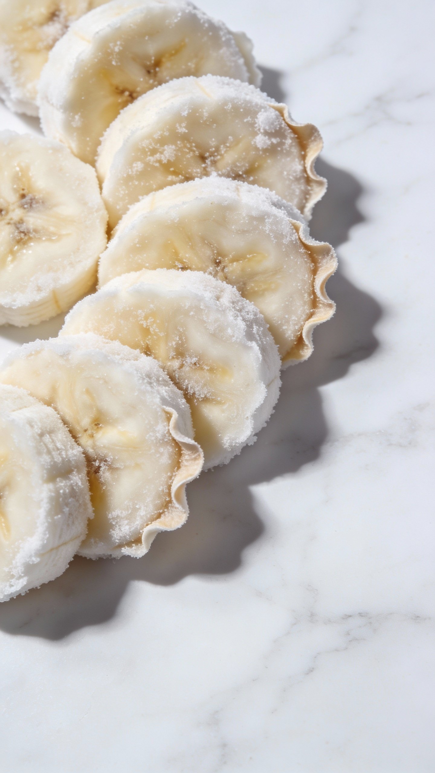 ripe frozen banana slices on white marble, closeup