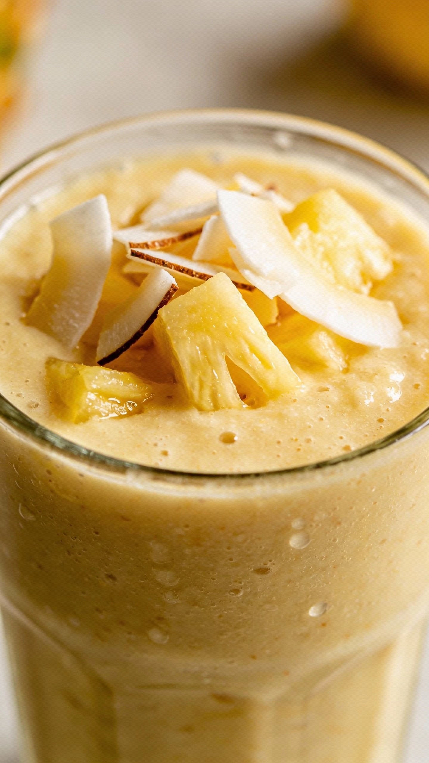 closeup pineapple coconut protein smoothie in clear glass